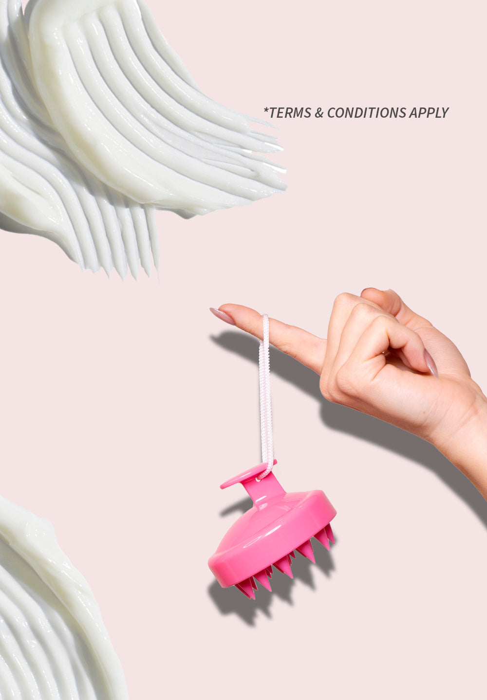 pink scalp brush dangling from a finger