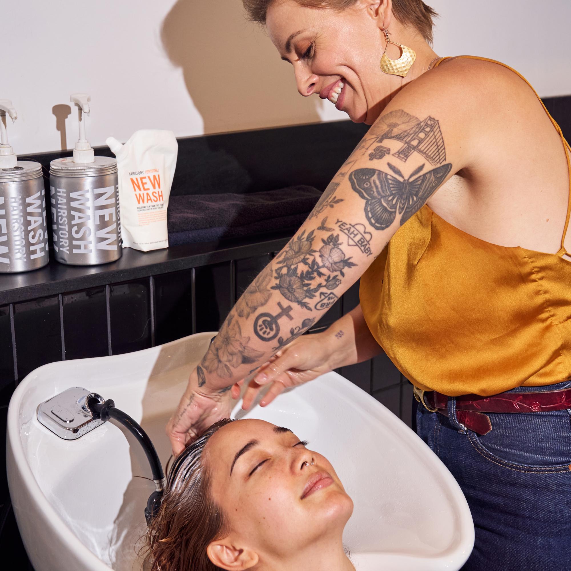 Hairdresser washing woman's hair with New Wash Original